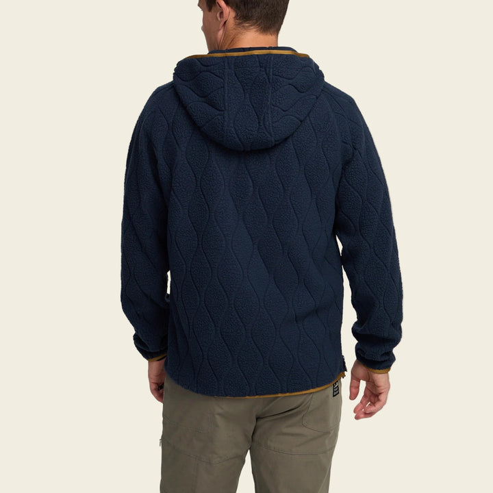 Person wearing a navy quilted jacket on a white background