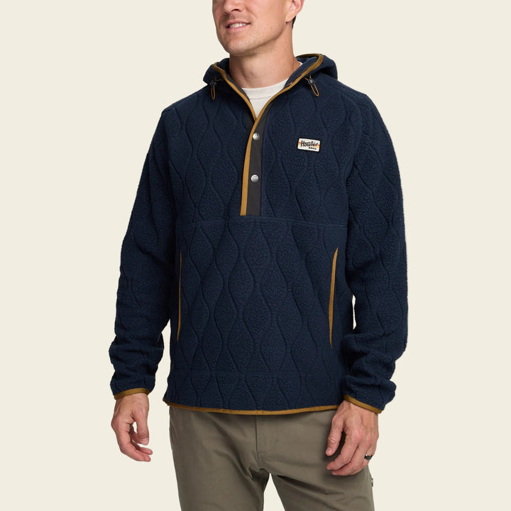 Man wearing a navy blue quilted pullover with brown accents on a white background