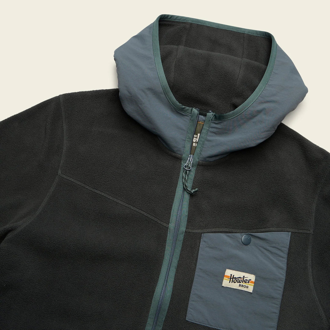 Black fleece jacket with a hood and visible brand logo on a beige background
