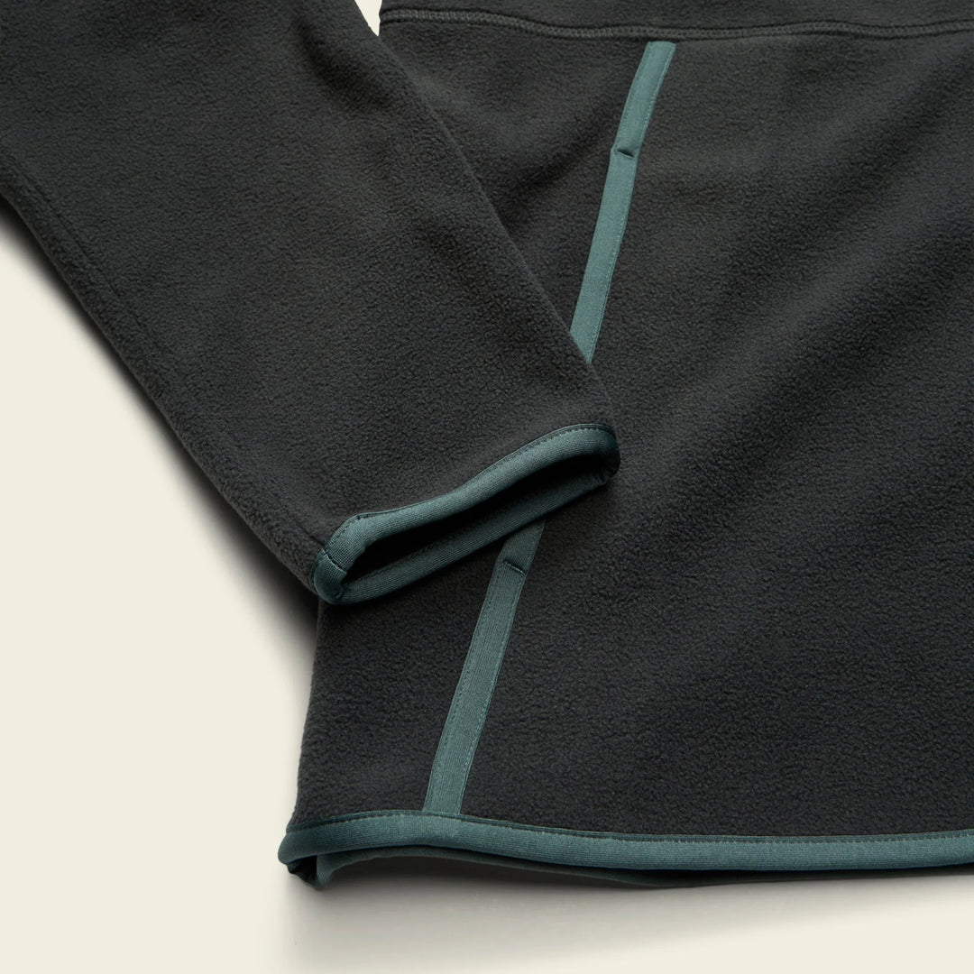 Dark gray fleece fabric with green trim on a beige background
