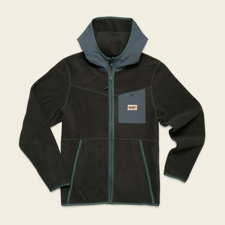 Black fleece jacket with green accents on a beige background