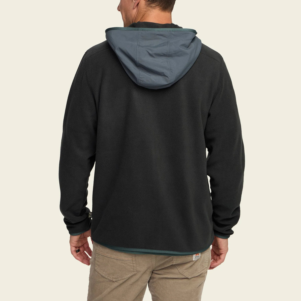 Person wearing a black hoodie with a gray hood on a beige background