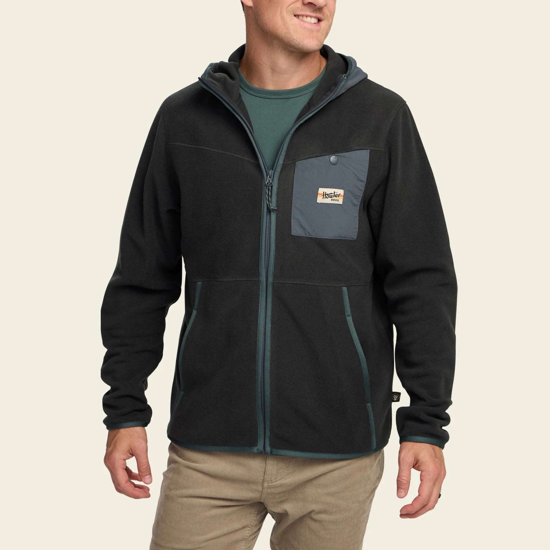 Man wearing a black jacket with a brand logo on a beige background