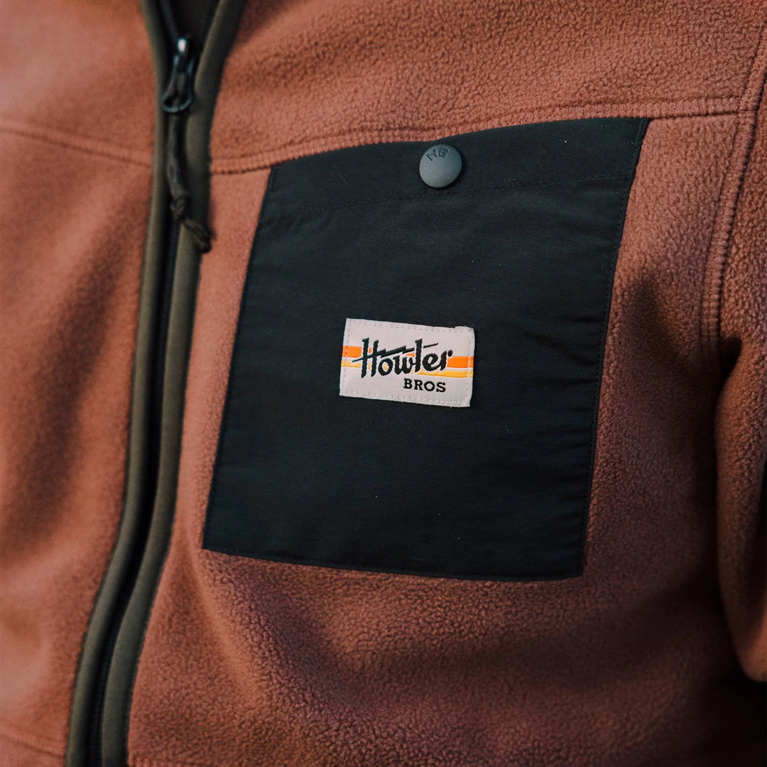 Close-up of a brown jacket with a black patch featuring 'Howler Bros' logo.