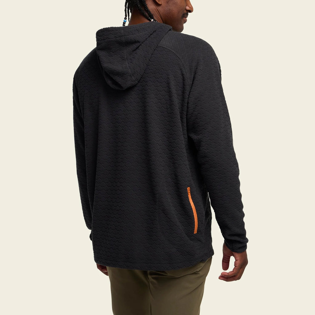 Person wearing a black hoodie with a visible brand logo on a beige background