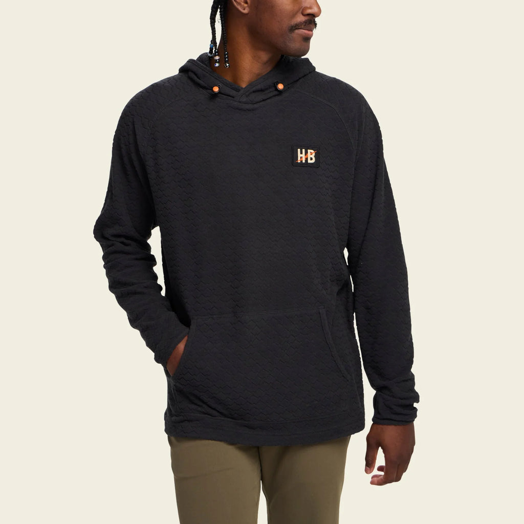 Person wearing a black hoodie with a logo on a beige background