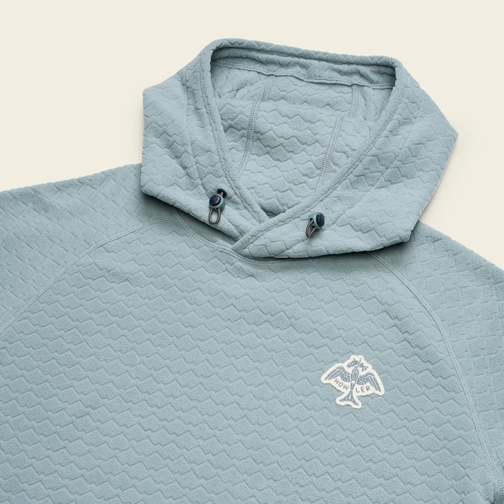 Light blue quilted jacket with a logo on a beige background