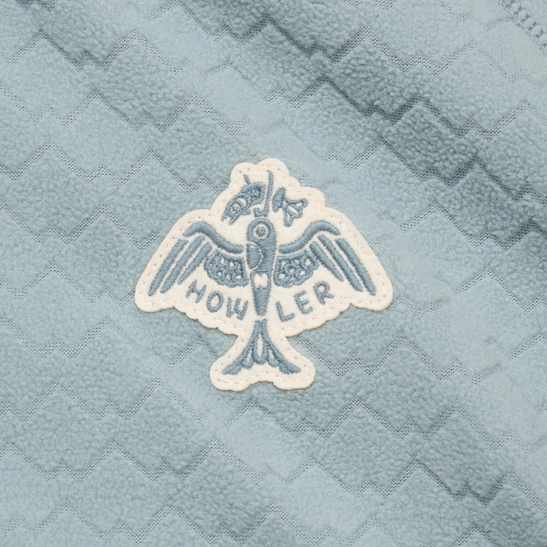Embroidered logo on a textured blue fabric background
