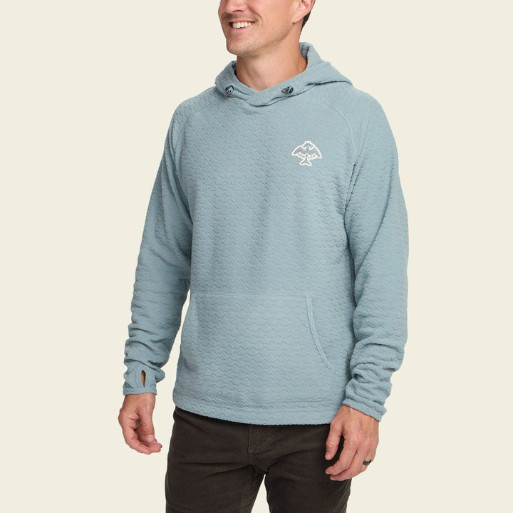 Man wearing a light blue hoodie with a logo on a beige background