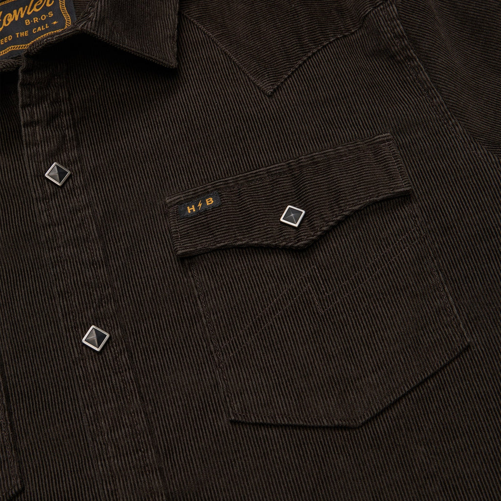 Close-up of a dark corduroy shirt with a pocket and brand label.