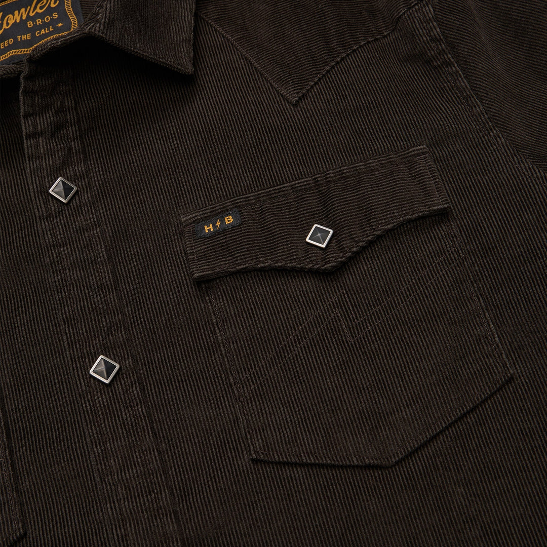 Close-up of a dark corduroy shirt with a pocket and brand label.