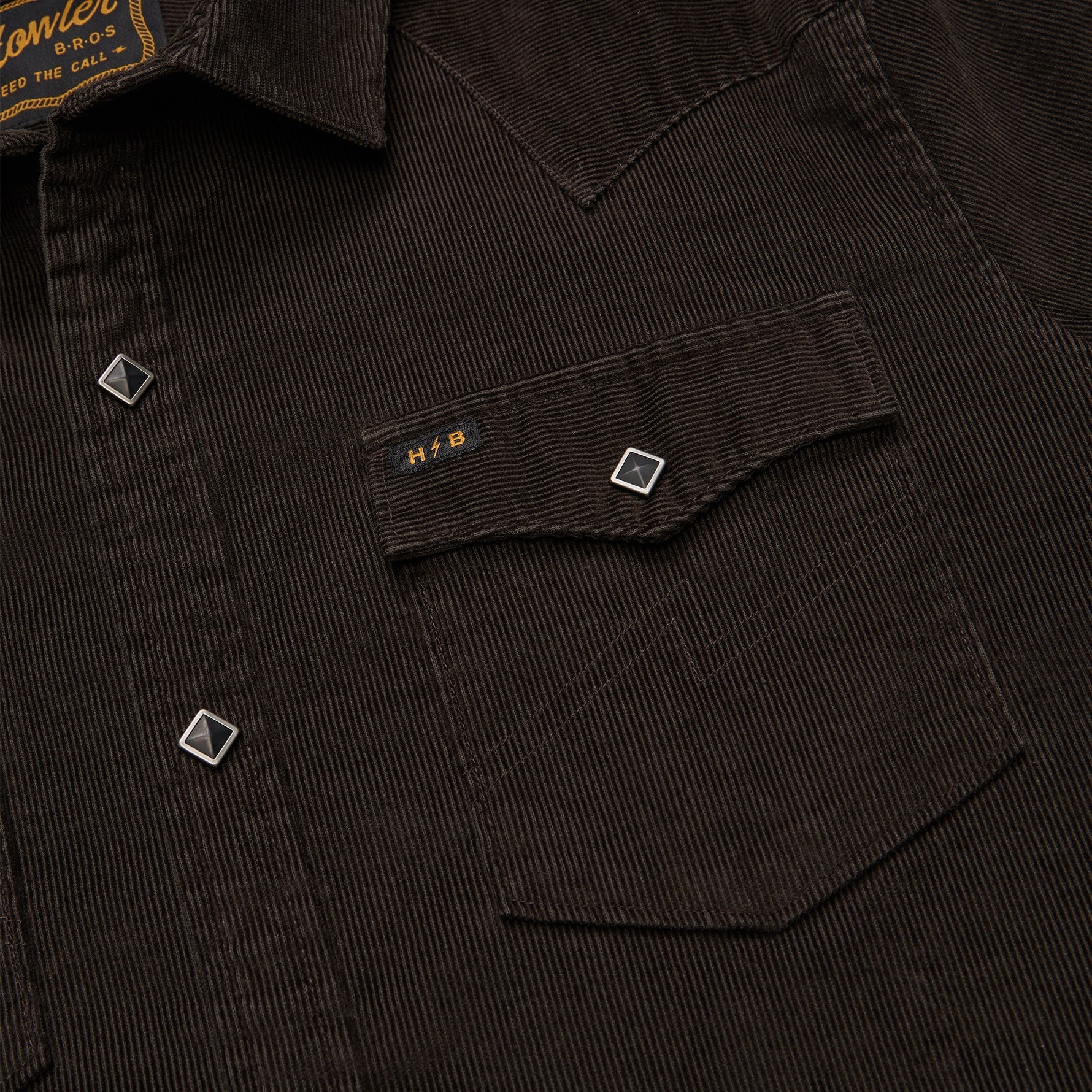 Close-up of a dark corduroy shirt with a pocket and brand label.