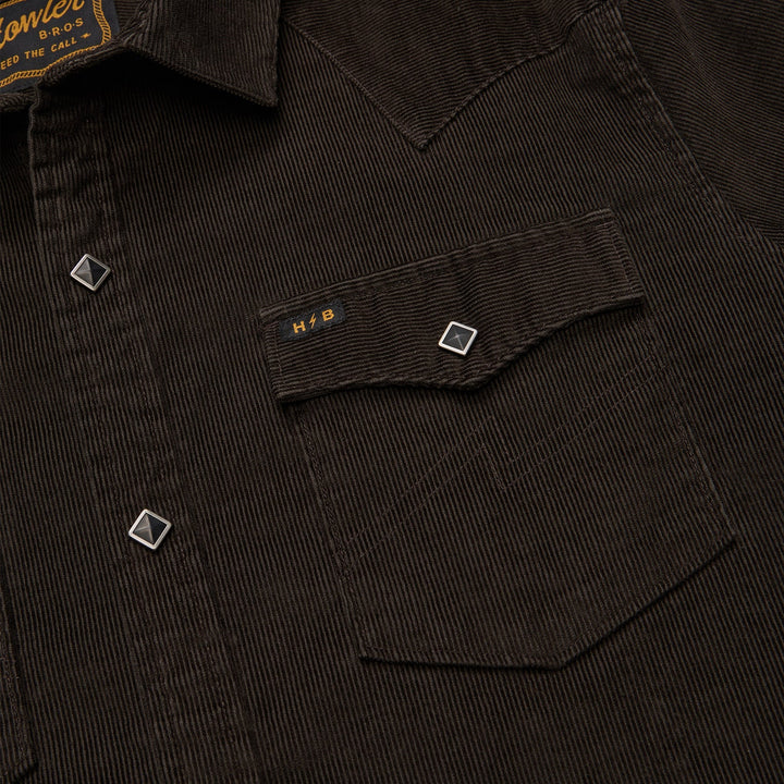 Close-up of a dark corduroy shirt with a pocket and brand label.