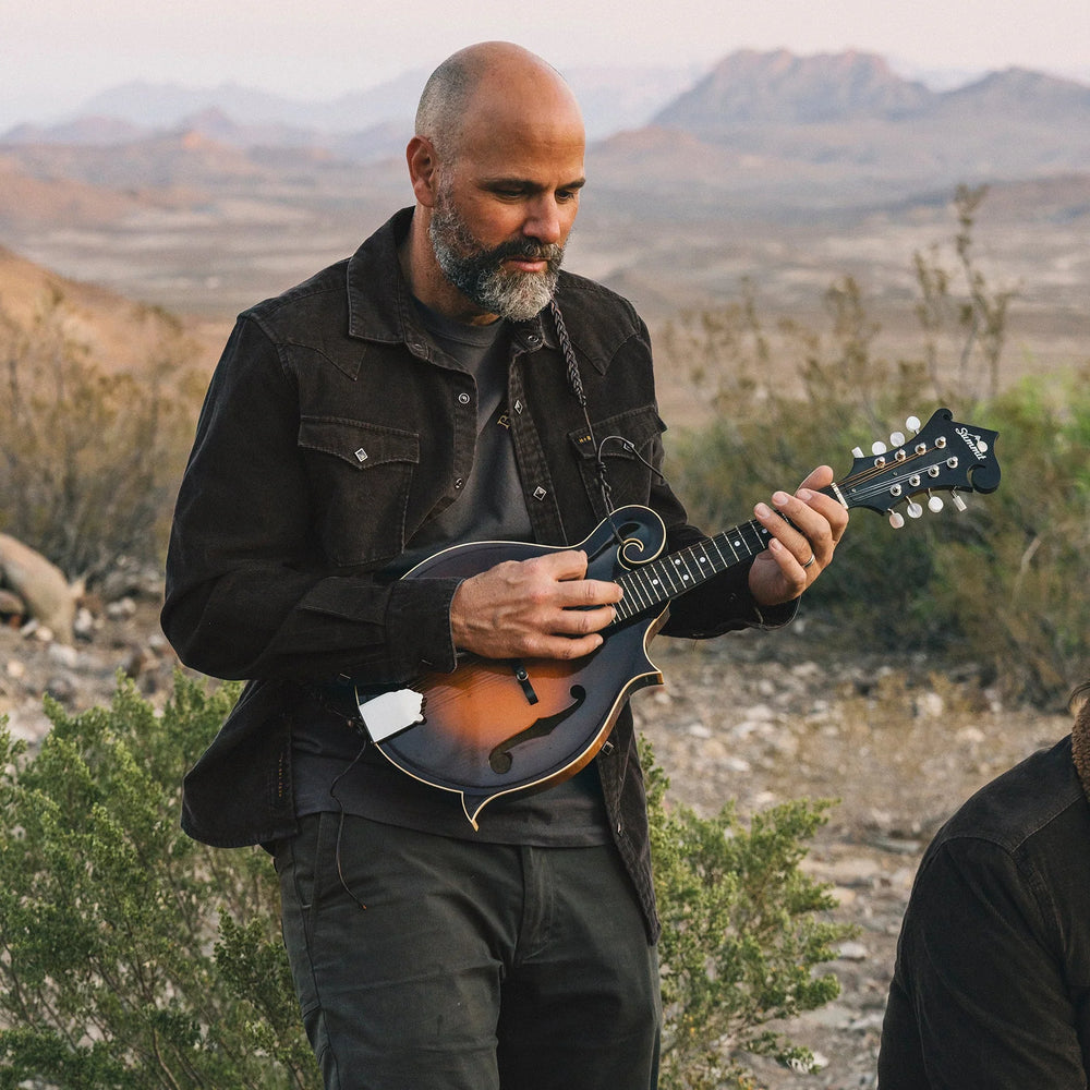 Man playing a mandolin in a desert landscape