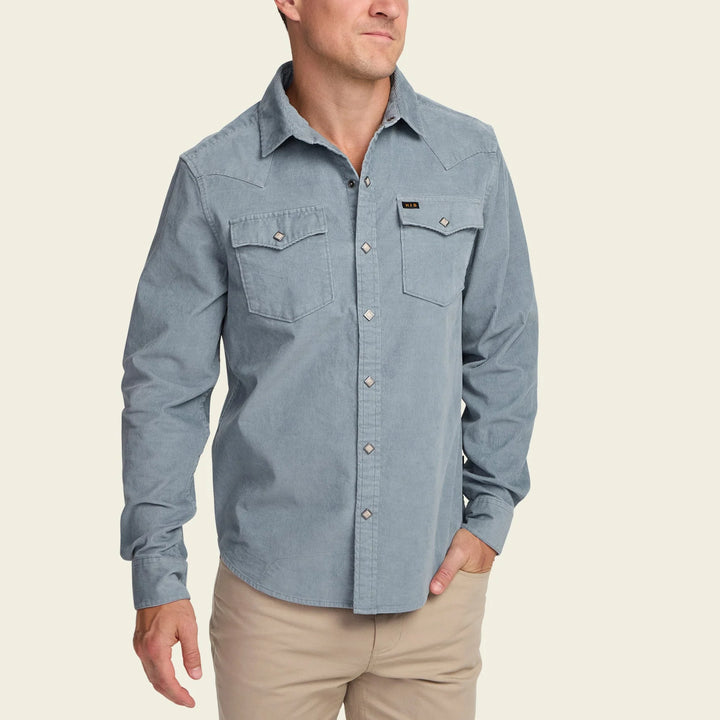 Man wearing a light blue button-up shirt with a beige background