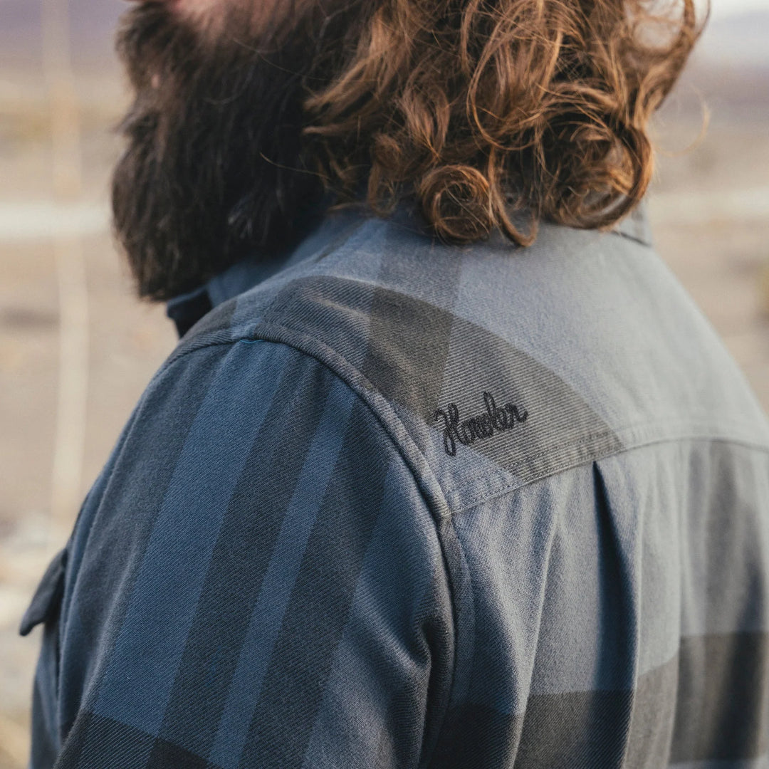 Person wearing a flannel shirt with 'Howler' branding on the shoulder, standing outdoors.