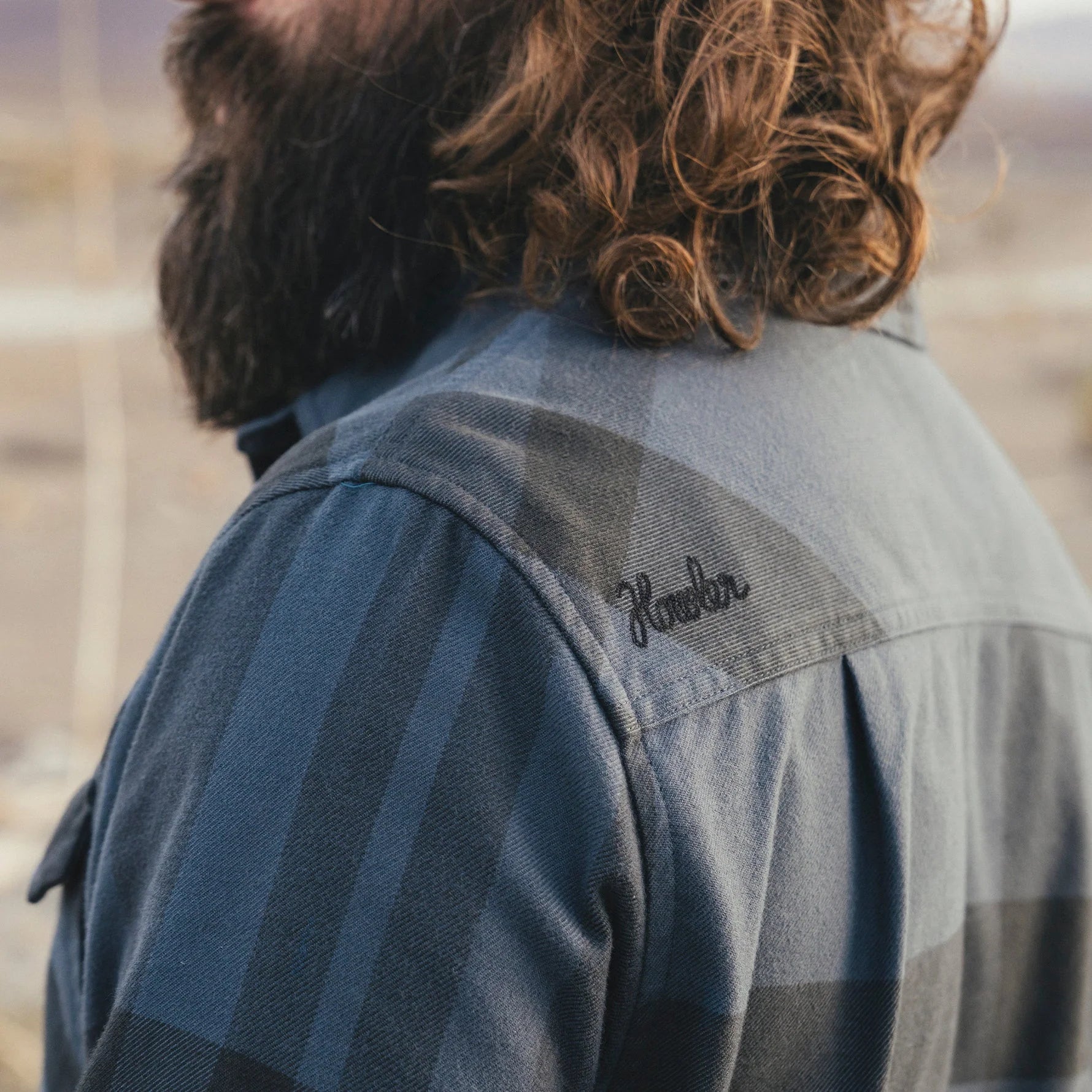 Person wearing a flannel shirt with 'Howler' branding on the shoulder, standing outdoors.