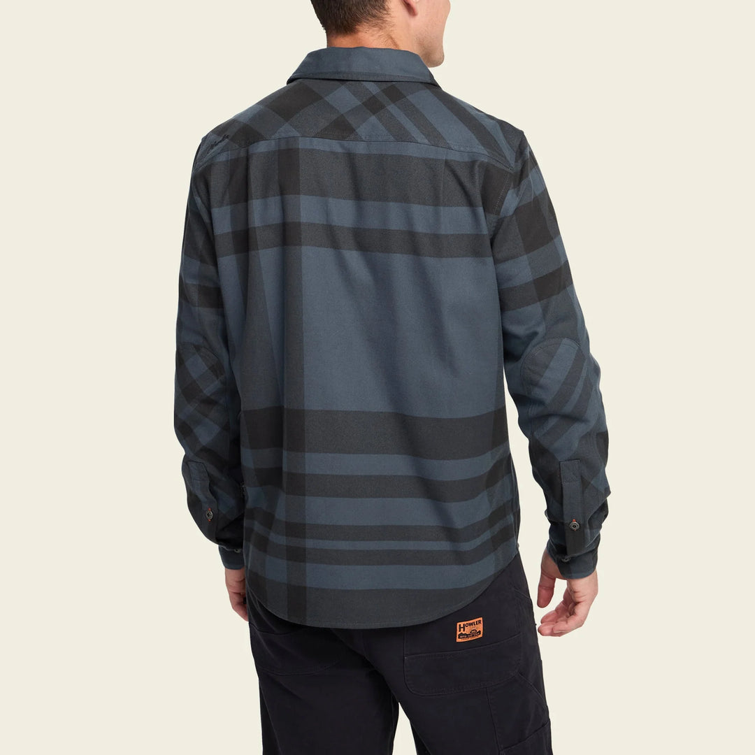 Person wearing a plaid shirt with a visible brand logo on a beige background