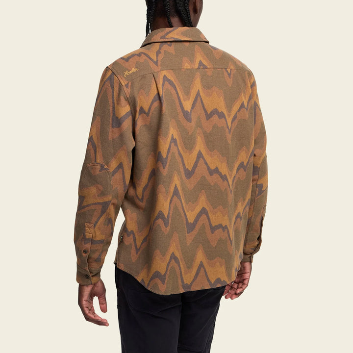 Person wearing a patterned brown shirt on a beige background