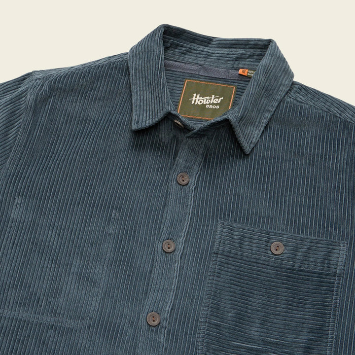 Blue corduroy shirt with a brand label on a beige background