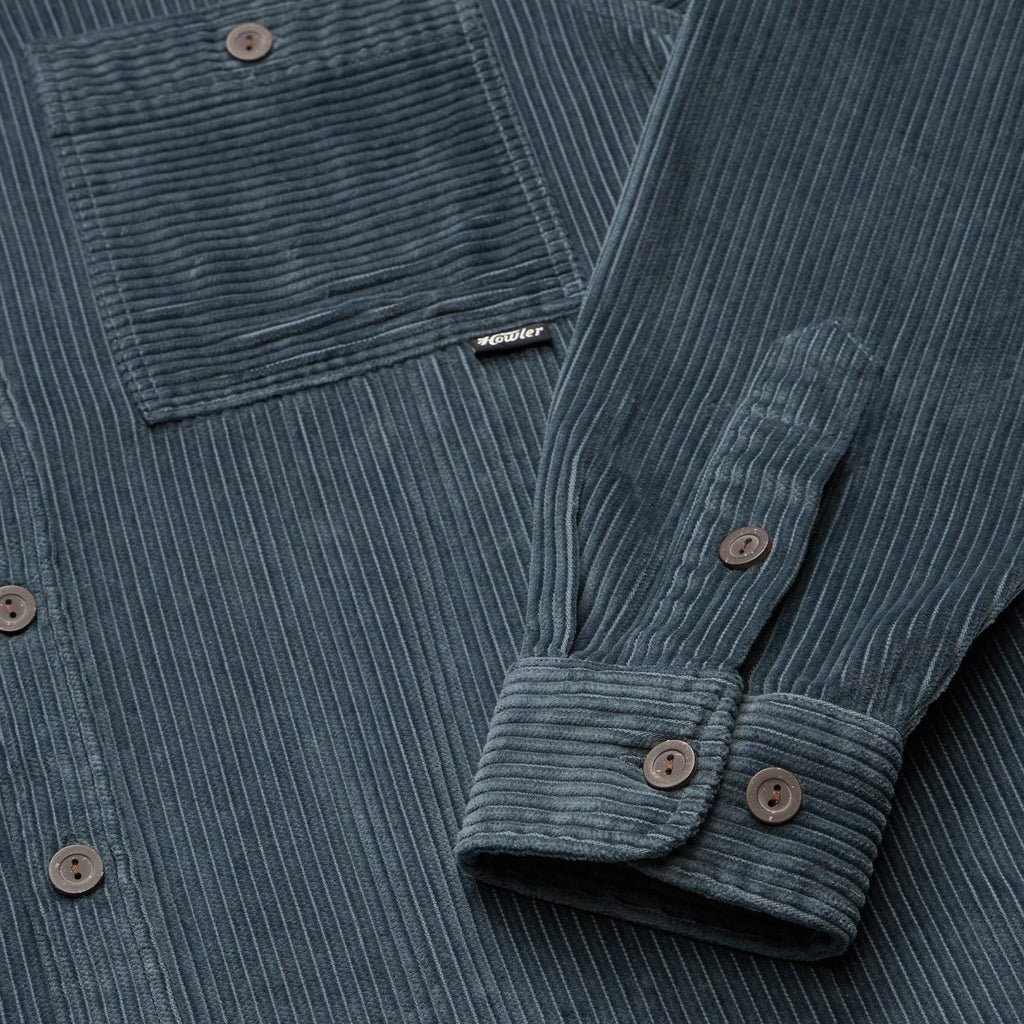 Close-up of a blue corduroy shirt with a brand label on the chest pocket.
