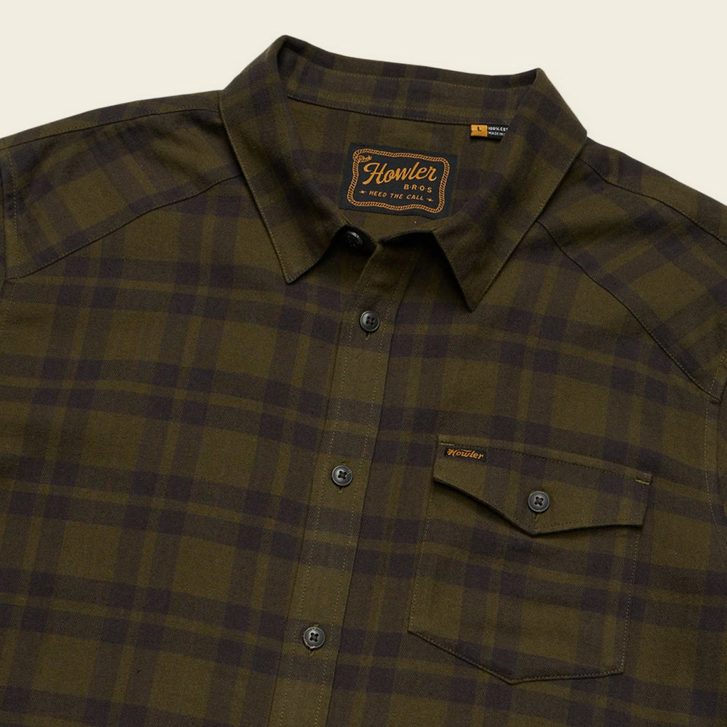 Green Howler Brothers plaid shirt with a brand logo on a beige background
