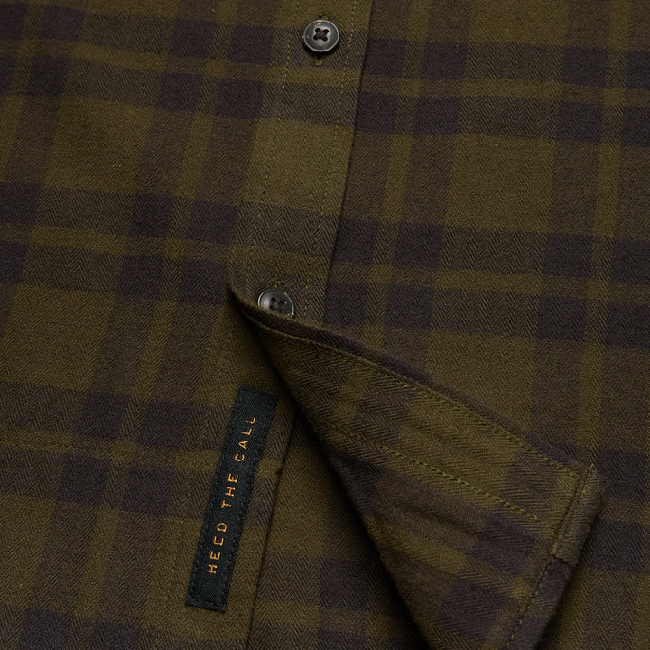 Close-up of a plaid shirt with a brand label on a dark background