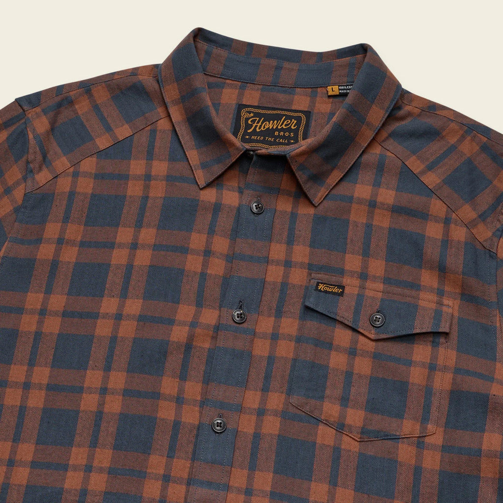 Howler Brothers plaid shirt with visible brand logo on a beige background