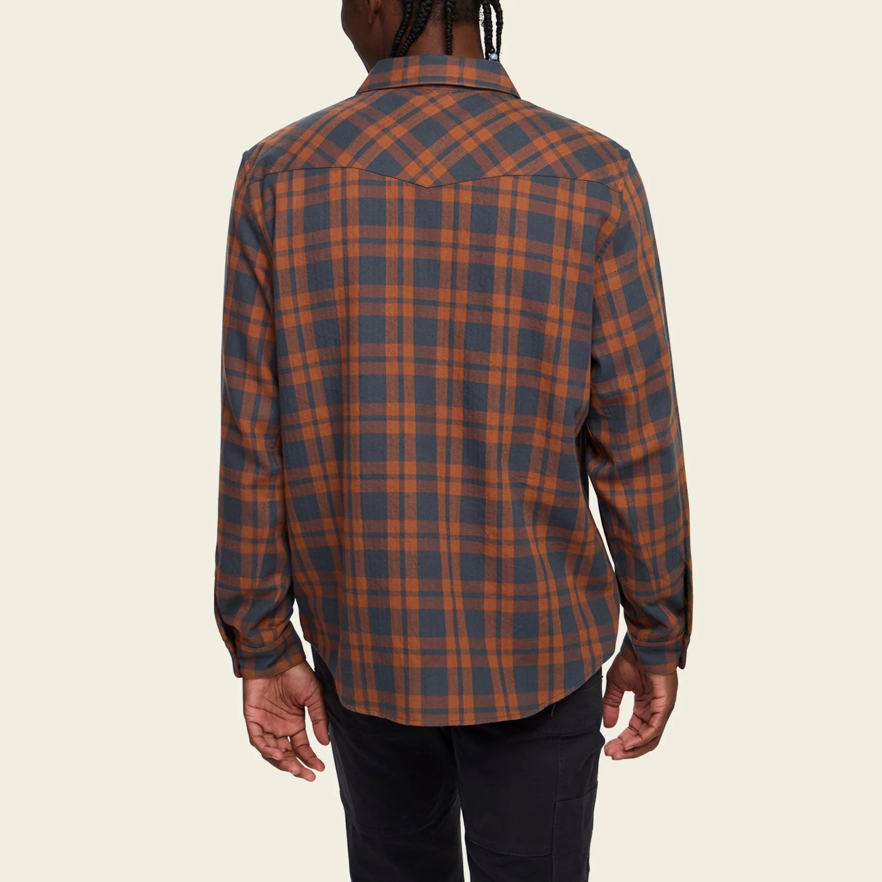 Person wearing a Howler Brothers  plaid shirt with a neutral background