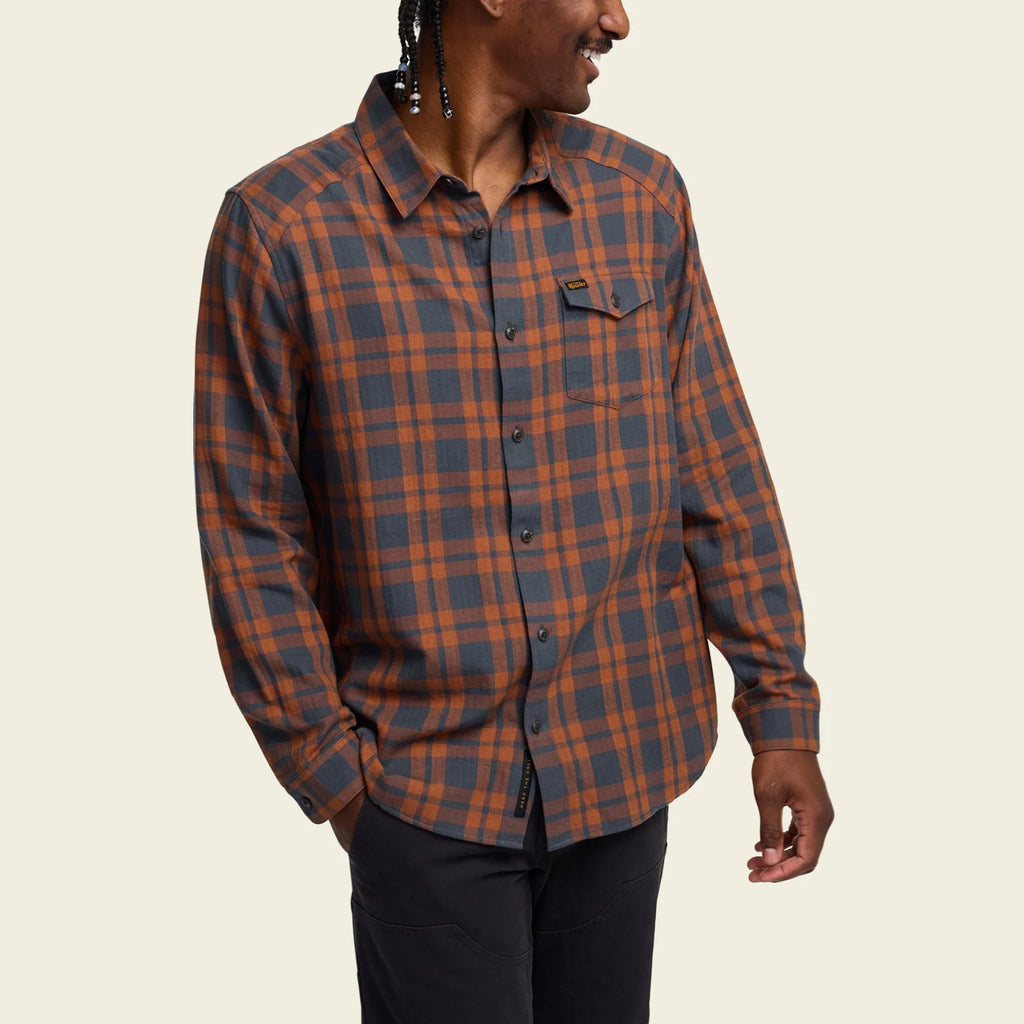 Person wearing a Howler Brothers plaid shirt on a beige background