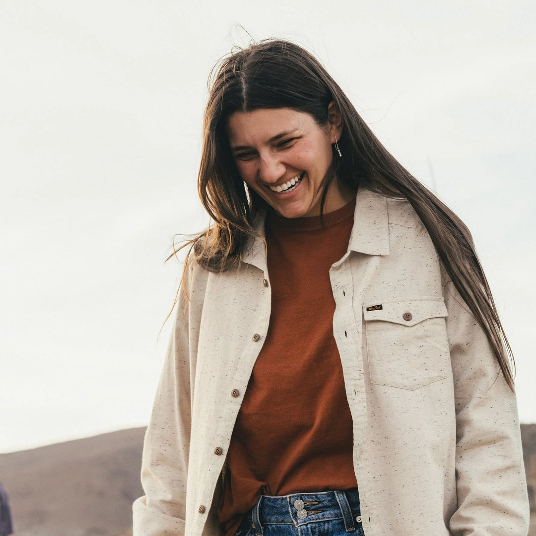 Woman wearing a beige jacket over a brown shirt with a neutral background