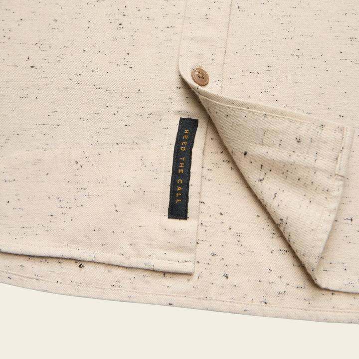 Close-up of a beige textured fabric with a button and 'Need The Call' label.