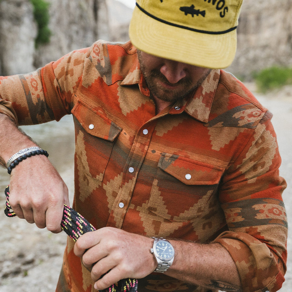 Man wearing a patterned shirt and yellow cap outdoors