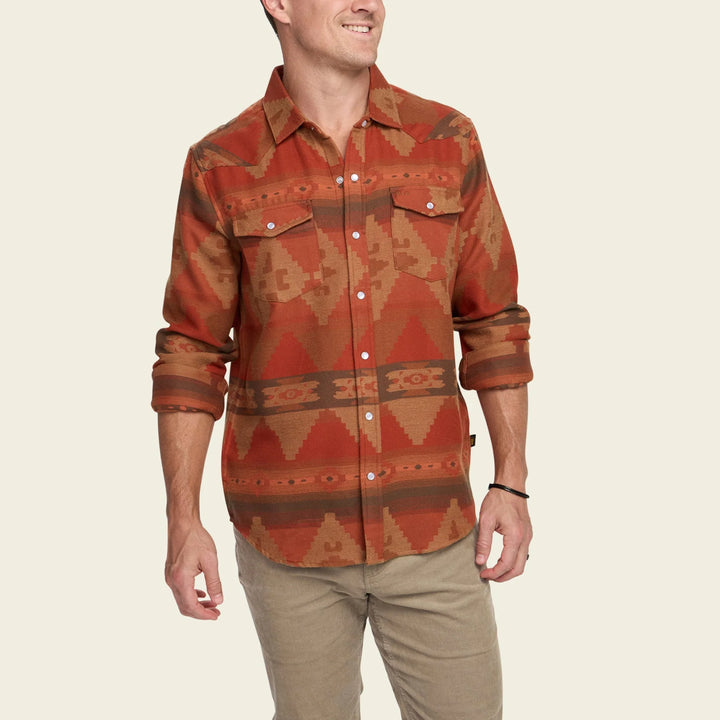 Man wearing a patterned shirt with rolled-up sleeves on a beige background