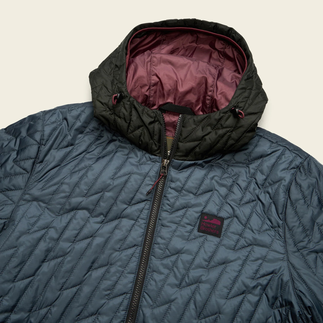Blue quilted jacket with black hood and maroon lining on a beige background