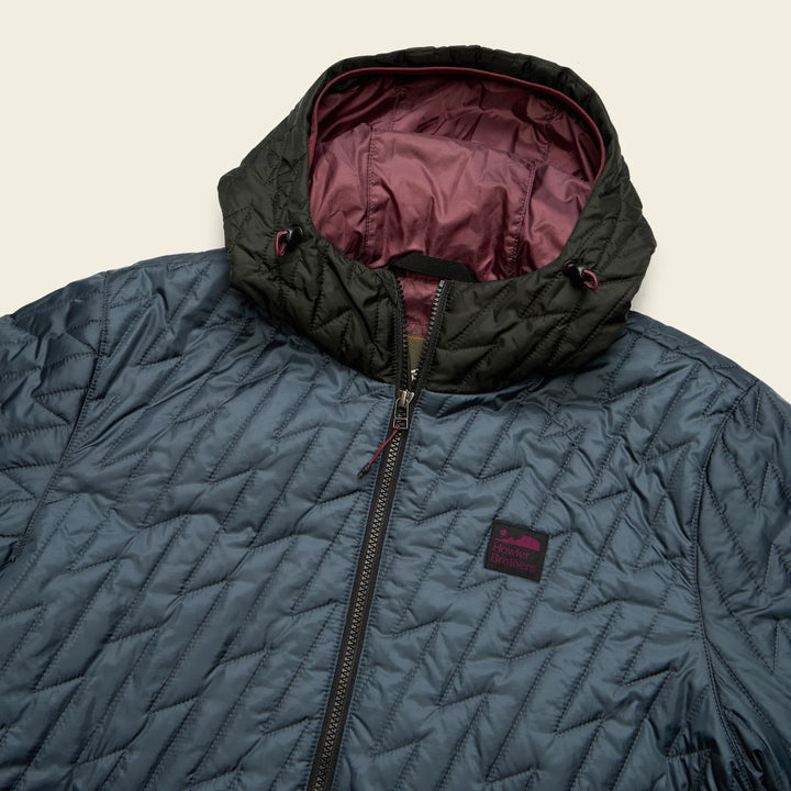 Blue quilted jacket with black hood and maroon lining on a beige background