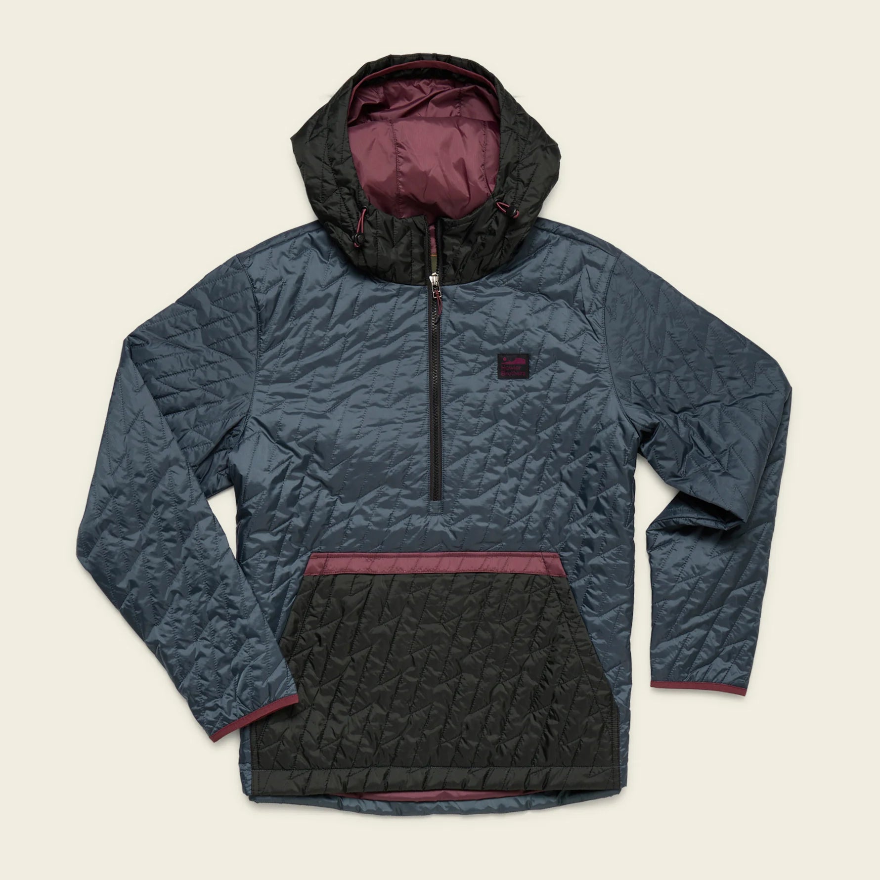 Howler Brothers Voltage Quilted Pullover jacket with a hood and contrasting inner lining on a beige background
