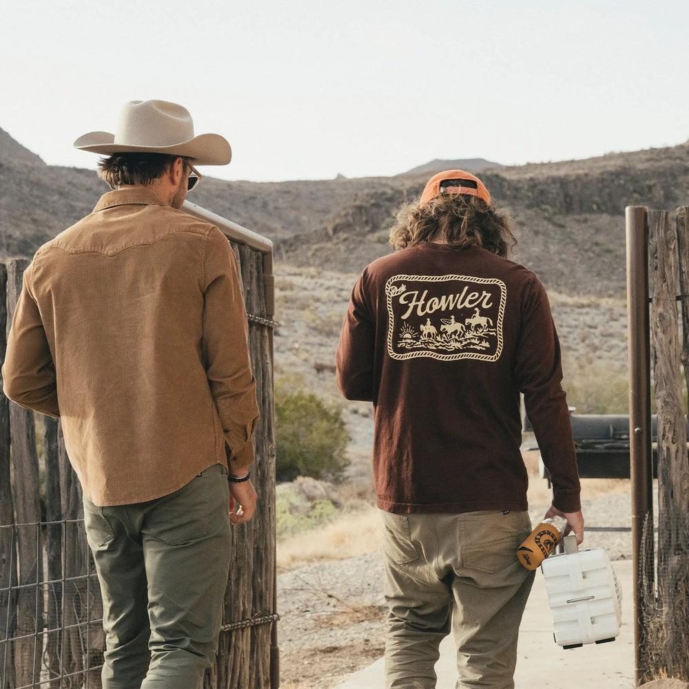 Two men in a desert setting, one wearing a cowboy hat and the other a 'Howler' branded shirt.