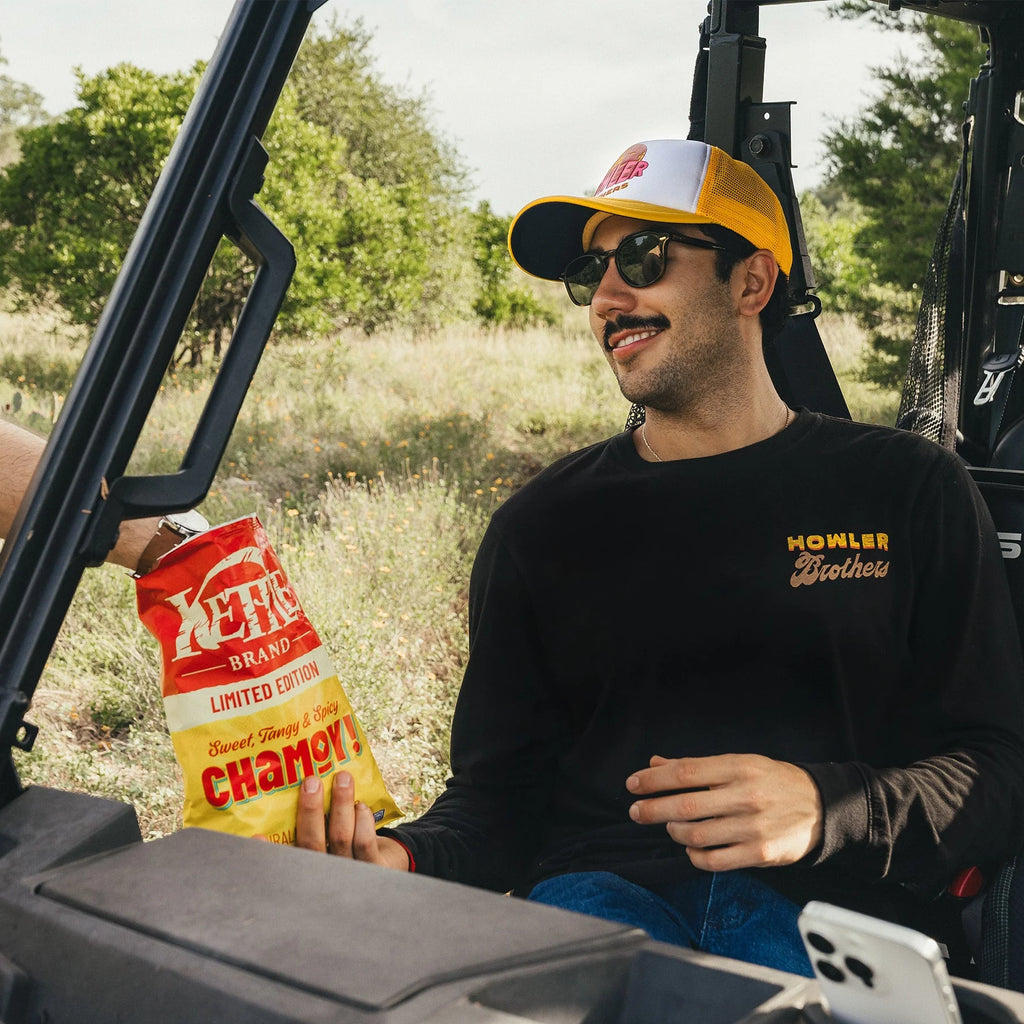 Man sitting in an off-road vehicle holding a Kero's Chamoy bag outdoors.
