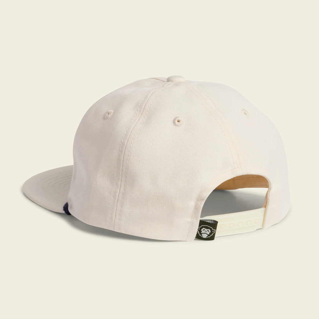 A light cream-colored baseball cap shown from the back, featuring a curved brim and an adjustable hook-and-loop strap closure with a small black brand tag.