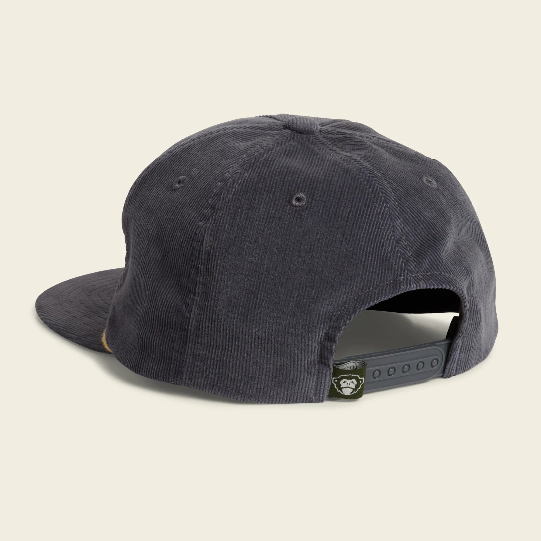 A dark charcoal gray corduroy baseball cap shown from a rear three-quarter angle on a white background, featuring an adjustable snapback closure with a small circular brand patch.