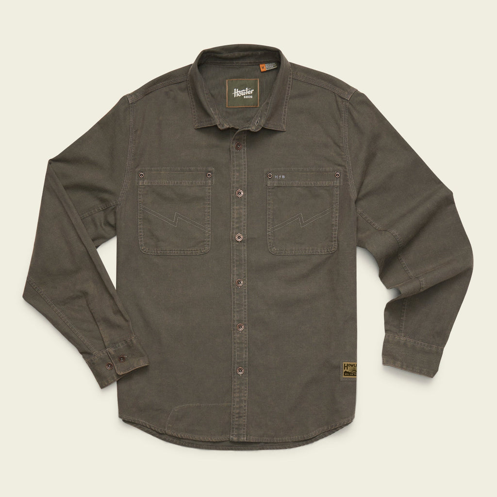 A dark olive brown long-sleeve button-up shirt with two chest pockets, laid flat on a light cream background. The brand 'Brixton' is visible on the inner neck label and a small patch near the lower right hem.