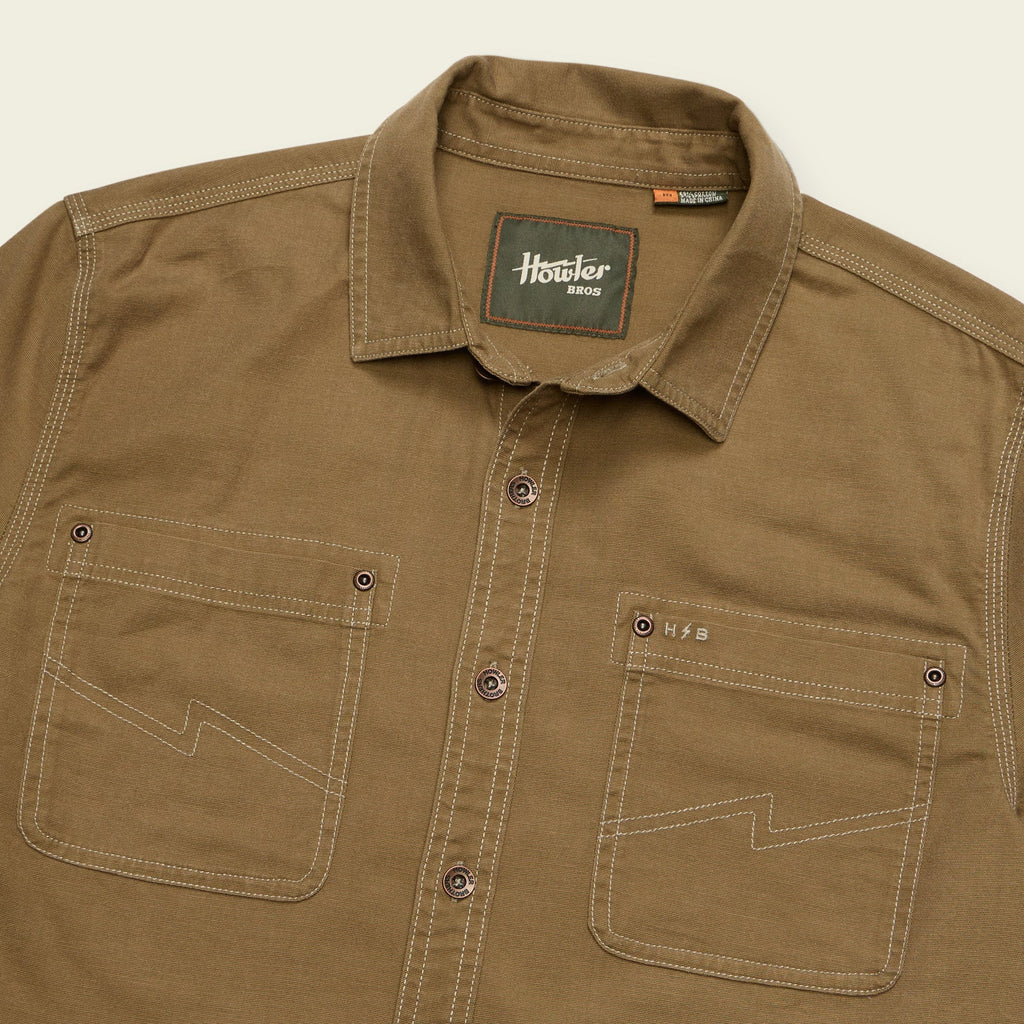 A close-up of a brown button-down shirt with contrast stitching, featuring two chest pockets and a visible 'Howler Ranch' neck label.