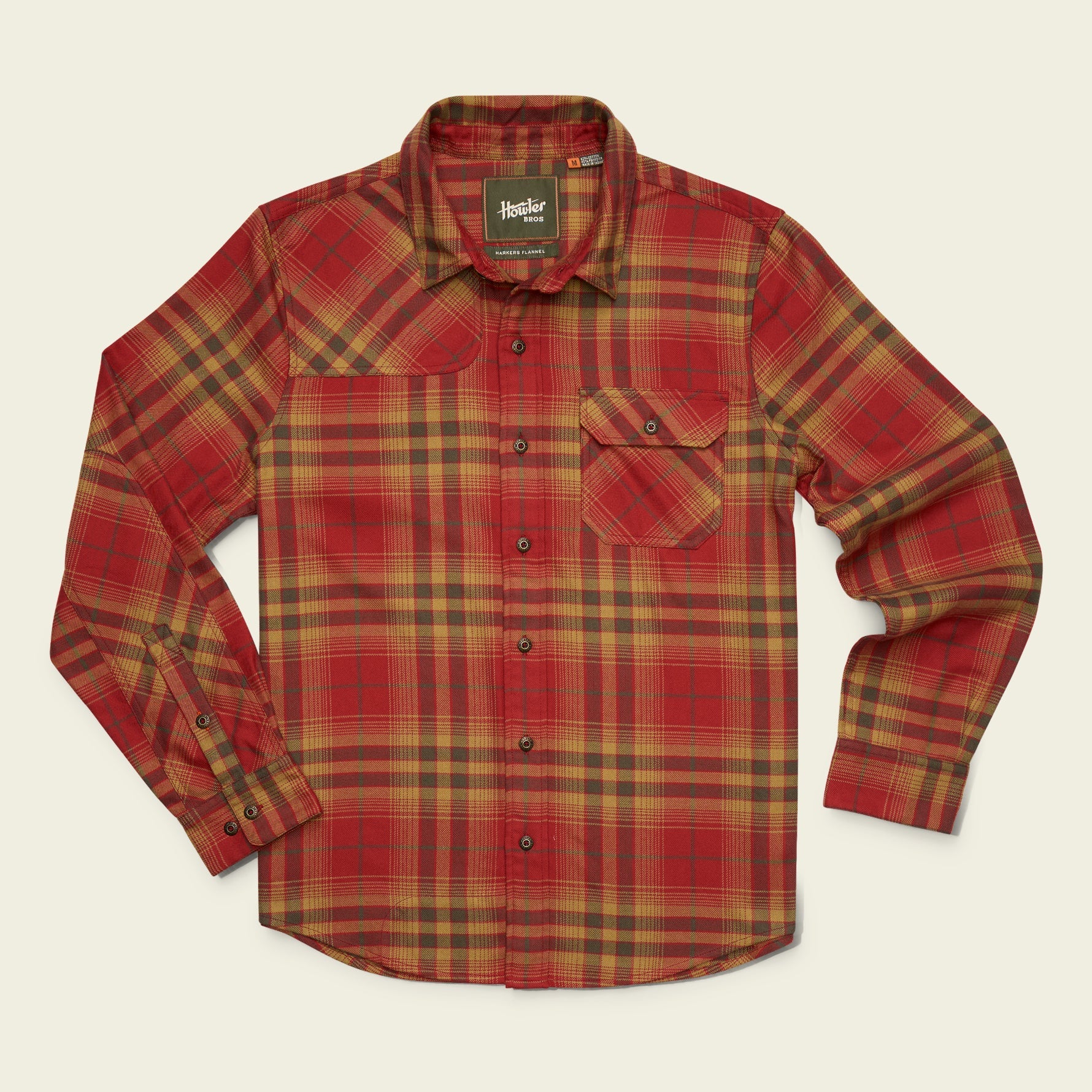A long-sleeve plaid flannel shirt by Marshall in red, yellow, and brown, laid flat against a light cream background.
