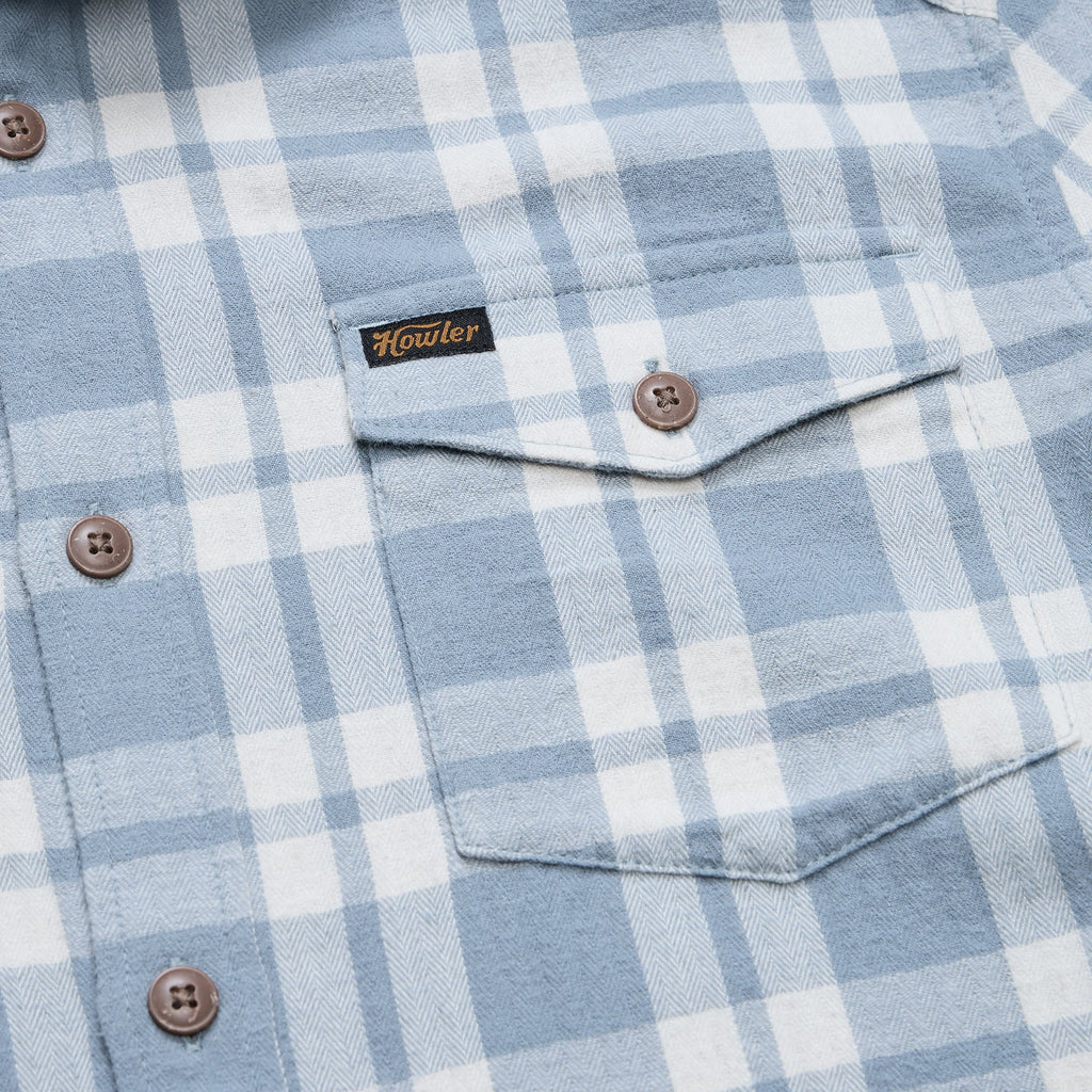 Close-up of a light blue and white plaid button-down shirt with a chest pocket and a visible Howler brand label.