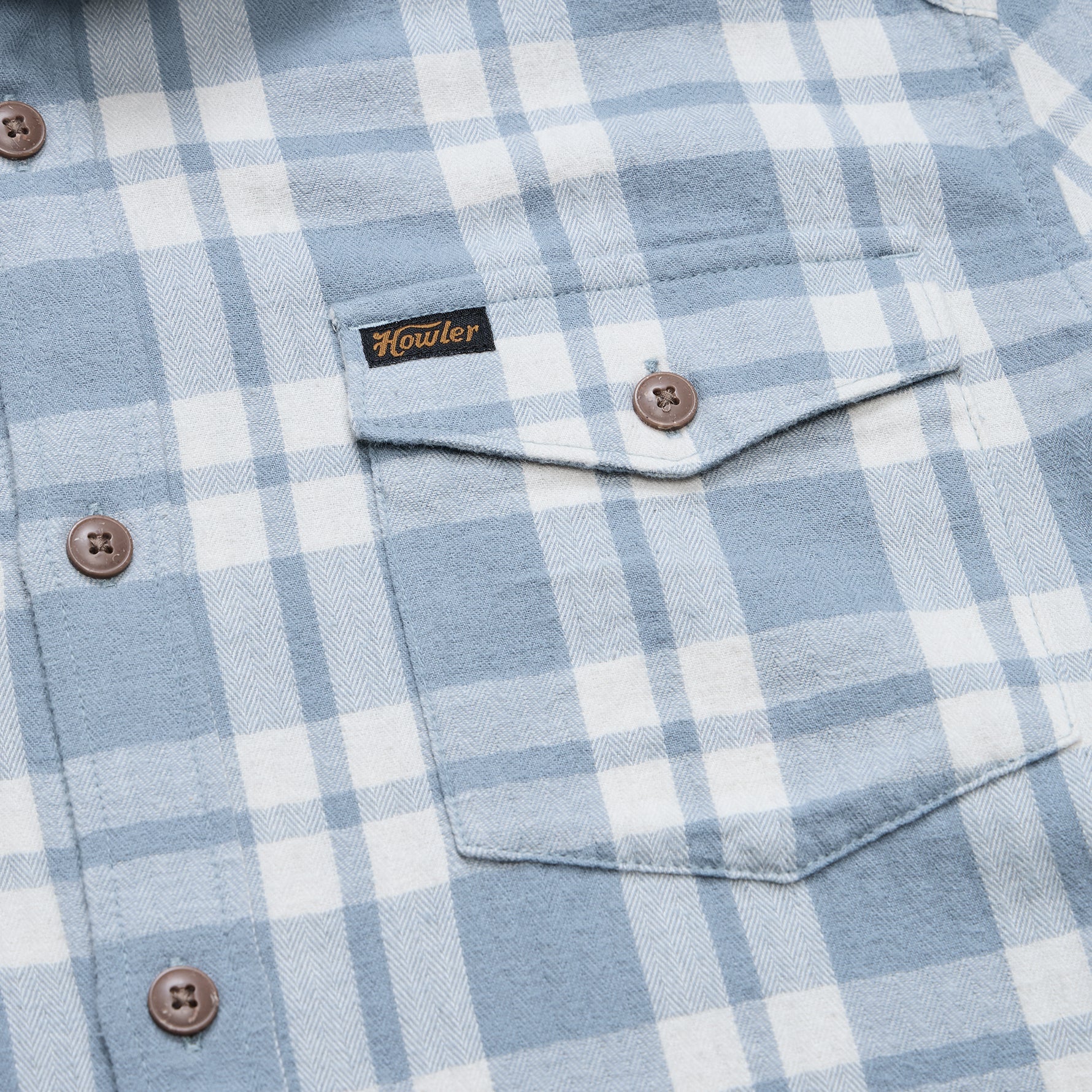 Close-up of a light blue and white plaid button-down shirt with a chest pocket and a visible Howler brand label.