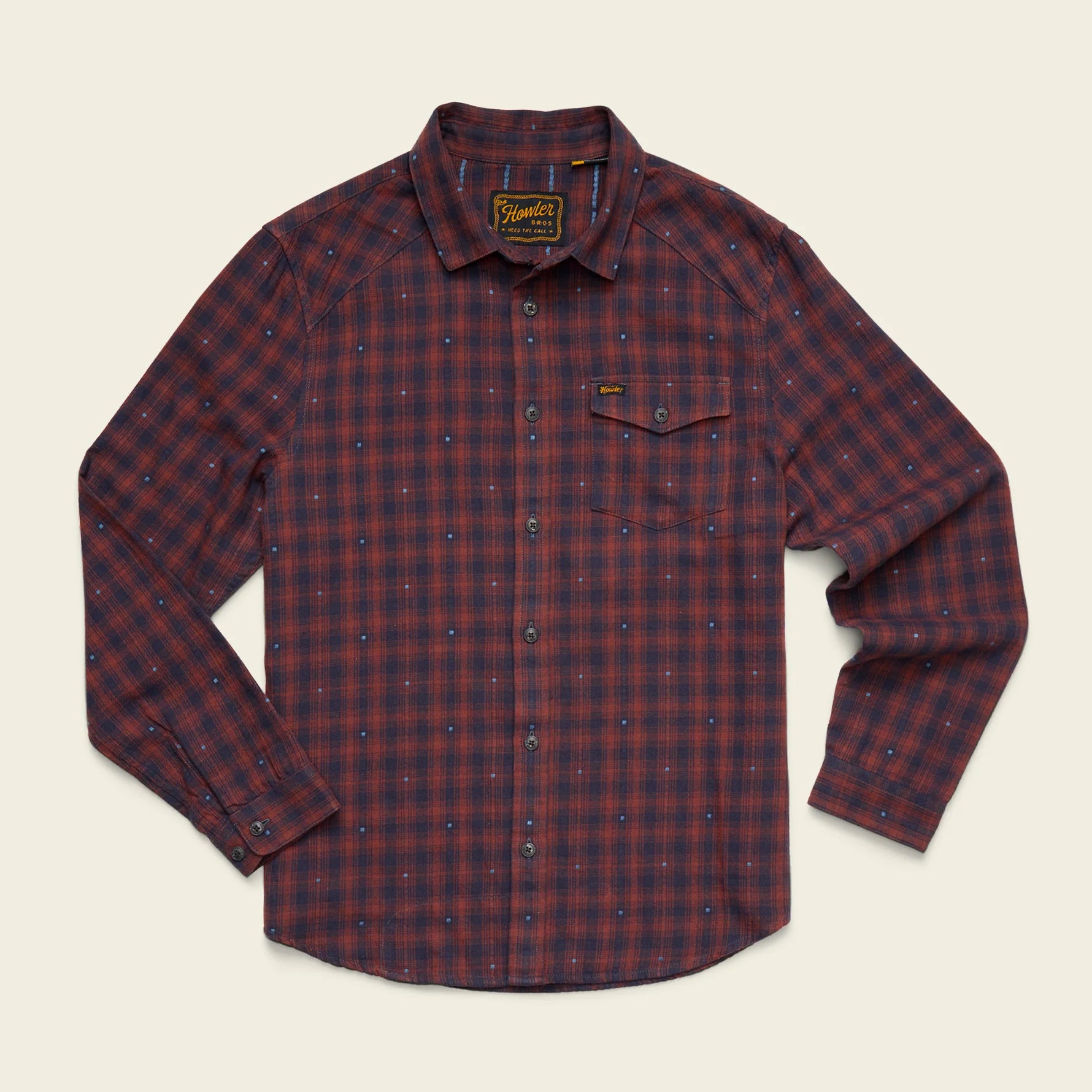 A long-sleeve button-up shirt by Barbour, featuring a red and navy blue plaid pattern with a subtle dotted texture, laid flat against a light cream background.