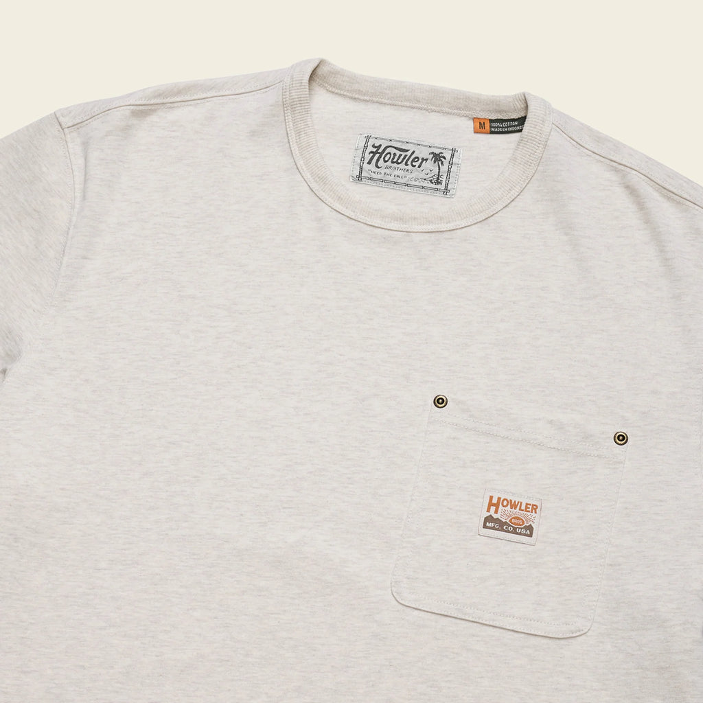 A close-up of a light heather gray crewneck t-shirt with a chest pocket featuring two metal snap buttons and a small Howler brand patch.