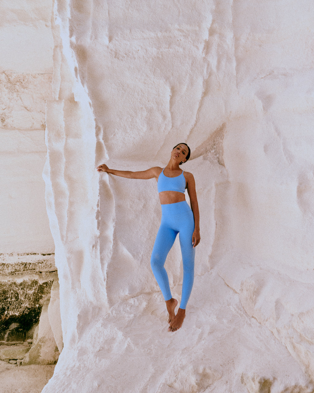 Person in blue athletic wear standing against a white rock wall