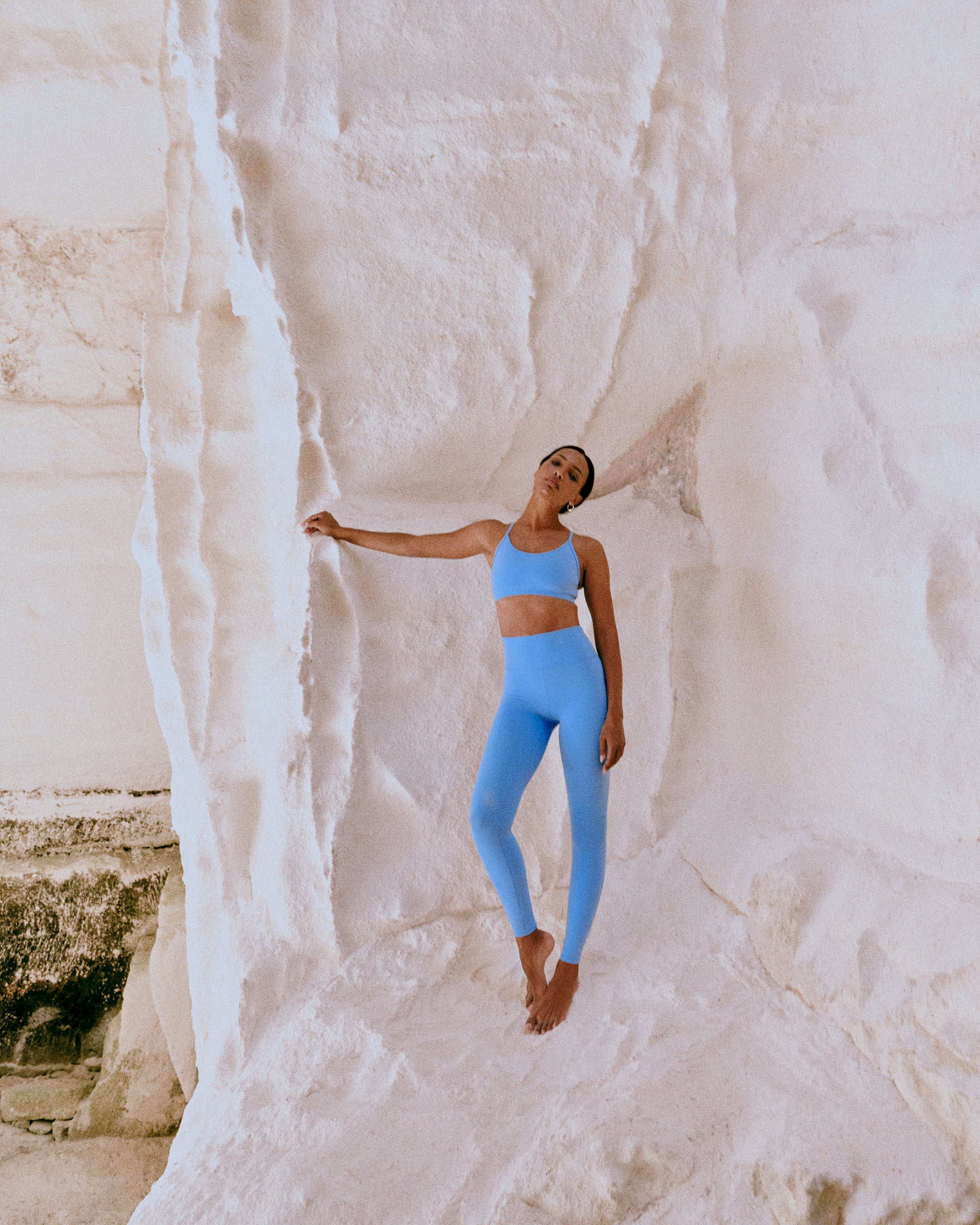 Person in blue athletic wear standing against a white rock wall